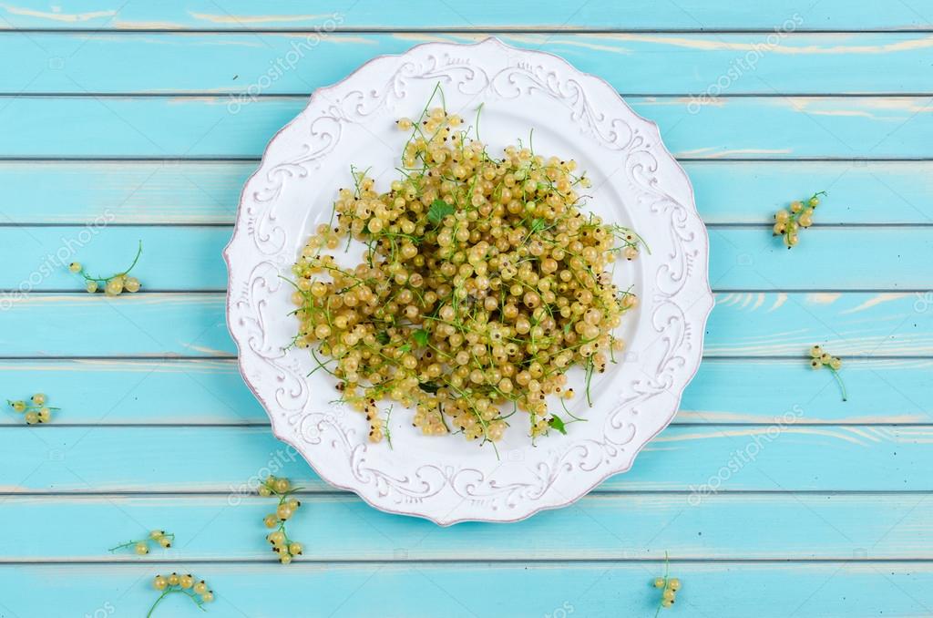 Fresh white currant on plate on rustic wooden turquoise table background