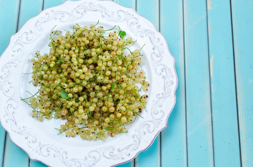 Fresh white currant on plate on rustic wooden turquoise table background