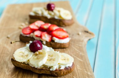 Bruschetta peynir ricotta, çilek ve muz ahşap turkuaz masa üzerinde