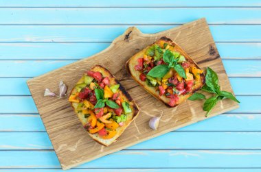 Italian bruschetta with chopped tomatoes and basil on wooden cutting board