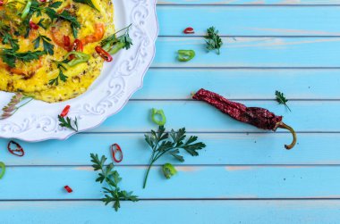 Omelette with tomatoes, chili on plate over wooden turquoise background