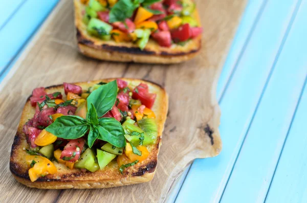 Italian bruschetta with chopped tomatoes and basil on wooden cutting board