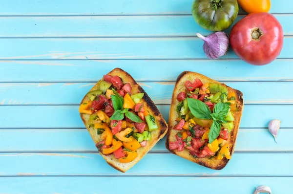 Bruschetta con tomates picados y albahaca sobre fondo turquesa de madera —  Fotos de Stock