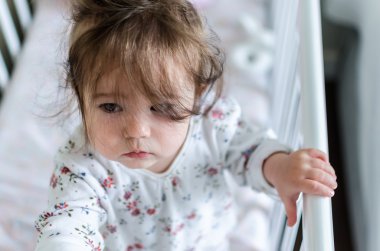 Portrait of adorable little baby girl staying at her bed