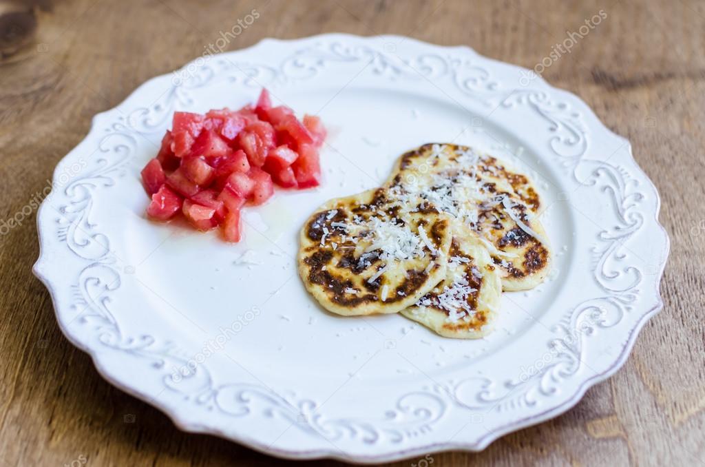 Ricotta pancakes with parmesan cheese and tomatoes salad on plat