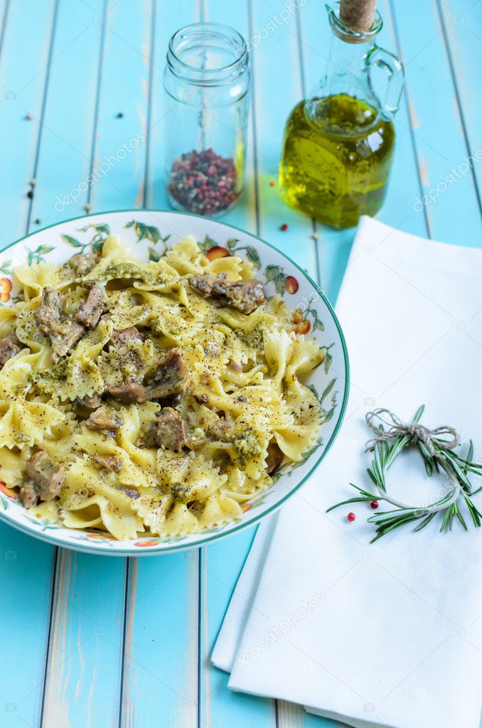 Pasta farfalle with turkey, pesto sauce and rosemary in serving plate over wooden turquoise background