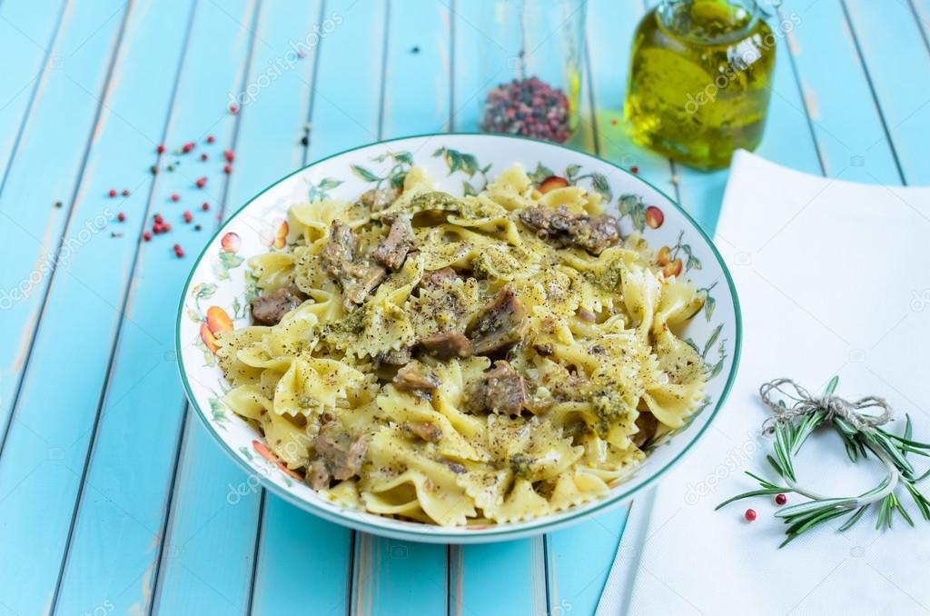 Pasta farfalle with turkey, pesto sauce and rosemary in serving plate over wooden turquoise background
