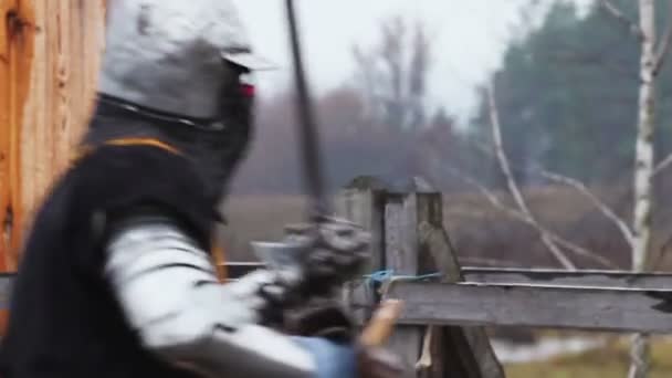 Два сильных рыцаря в стальных доспехах жестоко сражаются с мечами на поле боя — стоковое видео