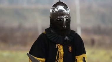 Metal ve ağır zırhlı cesur şövalye sokakta duruyor ve birini bekliyor