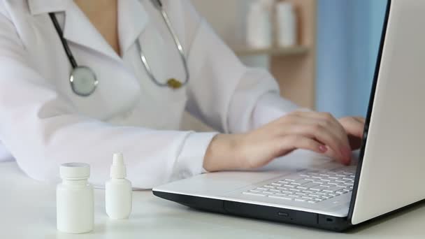 Женщина-врач заполняет онлайн рецепт, врач работает на ноутбуке — стоковое видео