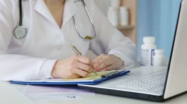 Kadın hekim kayıt yapıyor, tıbbi reçete yazıyor, form dolduruyor