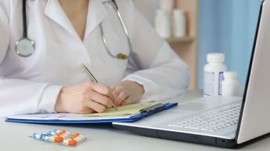Kadın hekim reçete yazıp hastaya veriyor. Misafir doktor