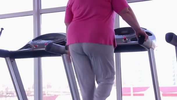 Жінка з жирним дном ходить на біговій доріжці, активне тренування втрати ваги в тренажерному залі — стокове відео
