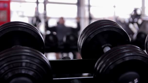 Silueta desenfocada del atleta masculino haciendo ejercicio de press de banca en el gimnasio — Vídeo de stock