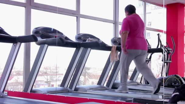 Dikke senior vrouw lopen op de loopband in de sportschool, actieve training voor weight loss — Stockvideo