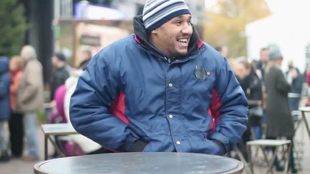 Optimistic migrant having fun at street festival, taking phone out of pocket — Stock Video