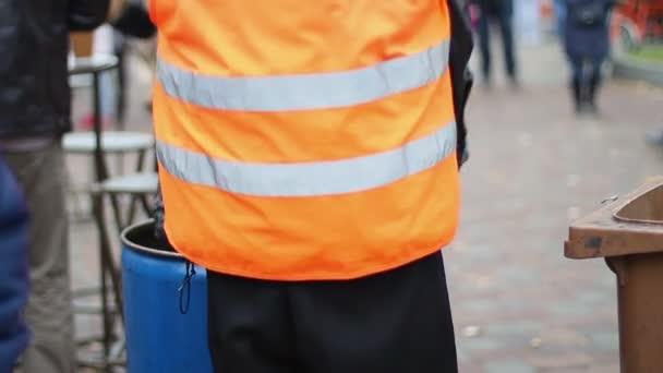 Street sweeper cleaning waste container in city square, working hard at low wage — Stock Video