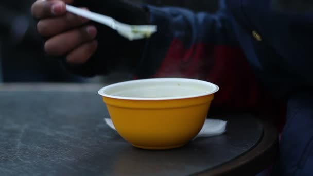 Pauvre homme affamé mangeant avec gourmandise de la soupe chaude dans un bol en plastique au refuge pour sans-abri — Video