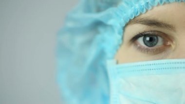 Kameraya bakarak yüz maskesi giyen kadın tıbbi işçinin yakın çekim shot