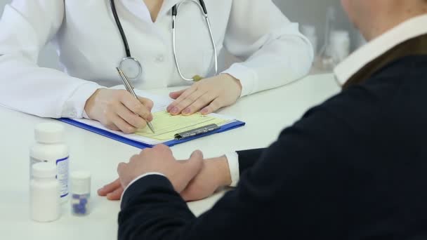 Mujer doctora consultando a paciente masculino sobre tratamiento médico, prescribiendo medicamentos — Vídeo de stock