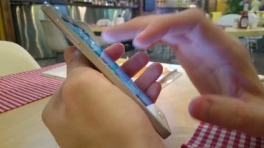 Sosyal ağlar smartphone üzerinde tarama restoranda oturan adam