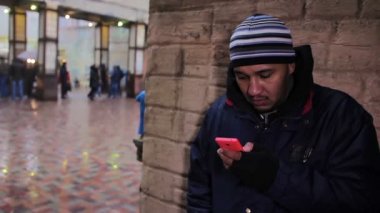 Arkadaşı için bekleyen ve cep telefonunu kontrol yalnız adam. Toplantı