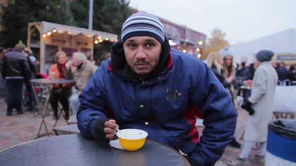 Hladový člověk jíst chutné polévky na ulici food festivalu. Smutek a samota — Stock video