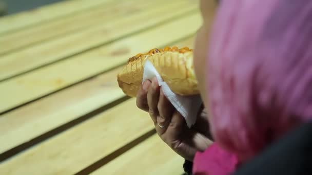 Mulher sem-abrigo a comer cachorro-quente no evento de caridade. Alimentos pouco saudáveis e insalubres — Vídeo de Stock