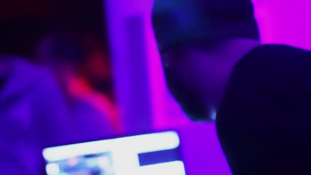 Männlicher DJ mit Kopfhörer, der Musik abspielt und Titel auf dem Laptop auswählt. Nachtclub — Stockvideo