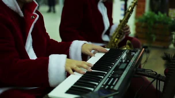 Muzikale band in Santa Claus suits spelen vrolijk melodie om Xmas sfeer te creëren — Stockvideo