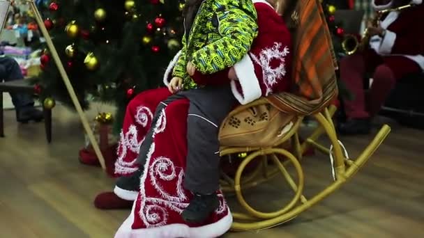 КИЕВ (УКРАИНА) - 19 декабря. Санта Клаус и дети. Веселый ребенок сидит на коленях Санта-Клауса, чтобы загадать желание Рождества, счастливое детство — стоковое видео