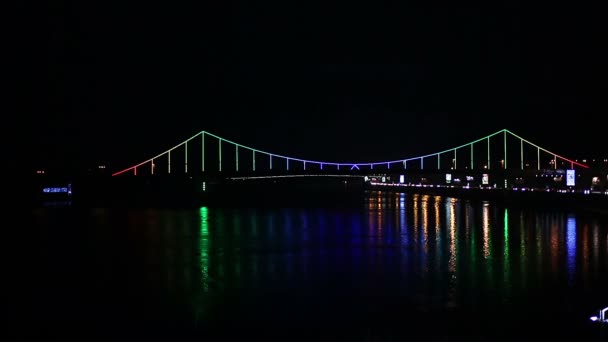 Όμορφο νυχτερινό αστικό τοπίο, φωτισμένη γέφυρα σε όλο το ποτάμι που λάμπει στο σκοτάδι — Αρχείο Βίντεο