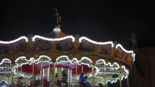 Kiev, Oekraïne-19 december 2015. Kinderen rijden carrousel. Gelukkige kinderen genieten van een ritje op Merry-go-round met ouders, pretpark — Stockvideo
