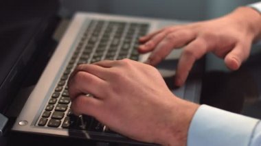 Yazarak, dizüstü bilgisayarda çalışan, touchpad kullanarak erkek ofis çalışanı