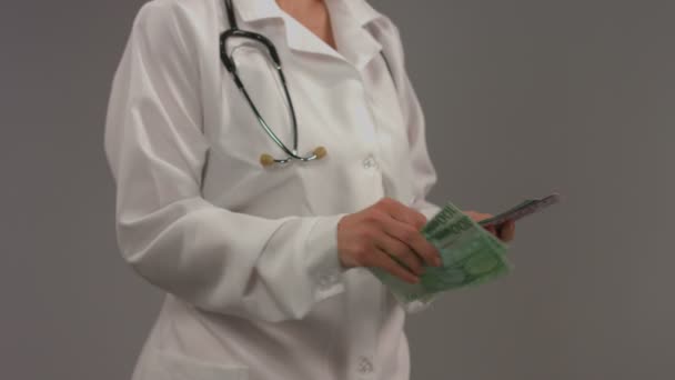Доктор в белом халате считает деньги. Коррумпированная система здравоохранения — стоковое видео