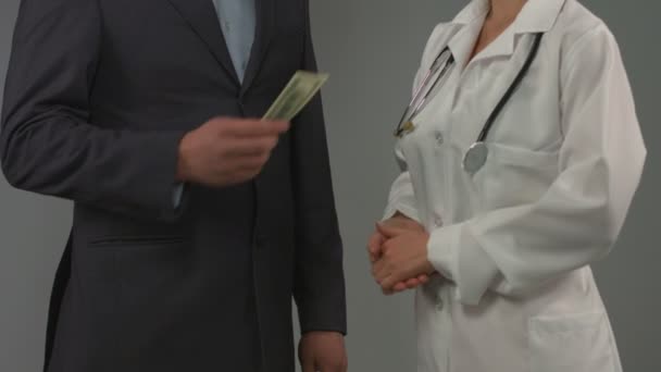 Patiënt geeft geld aan arts. Dure gezondheid verzekering, omkopen — Stockvideo