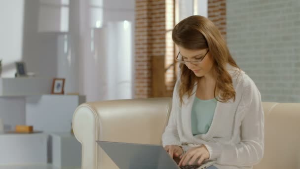 Joven chica bonita en gafas de chat en el ordenador portátil, sonrisa en la cámara — Vídeos de Stock