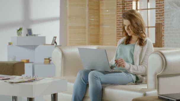 Jovem feliz sentada em casa, conversando no laptop, sorrindo — Vídeo de Stock