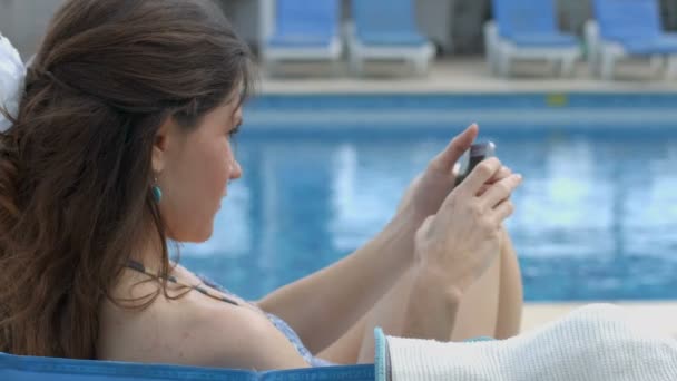 Красивая женщина набирает сообщение на смартфоне на летнем курорте — стоковое видео