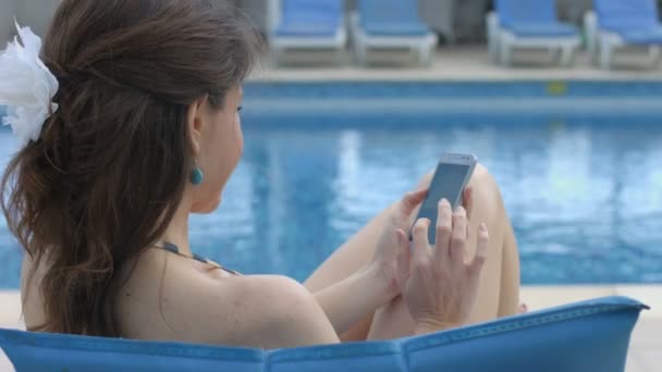 Счастливая молодая женщина болтает на смартфоне на пляже, улыбаясь — стоковое видео
