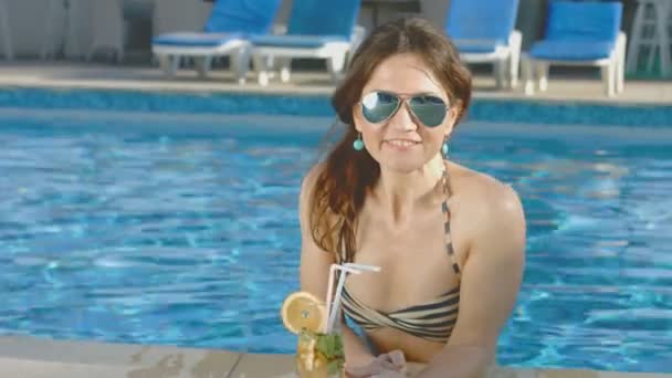 Beautiful girl bikini relaxes in pool, enjoys cocktail, vacation — Stock Video