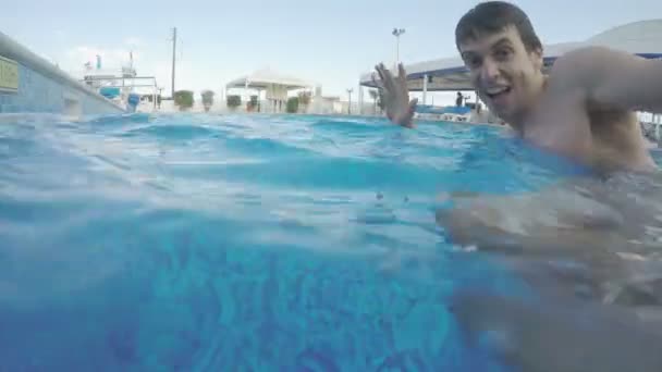 Happy guy swimming in pool, enjoying vacating at luxury resort — Stock Video