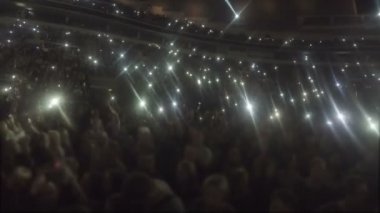 Stadyum insanlar sallayarak elleri dolu, karanlık, aşk şarkısı telefon ekranları Parlatıcı