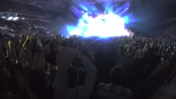 Багато схвильованих людей насолоджуються концертом, аплодуючи махаючи руками, рок-зірка на сцені — стокове відео