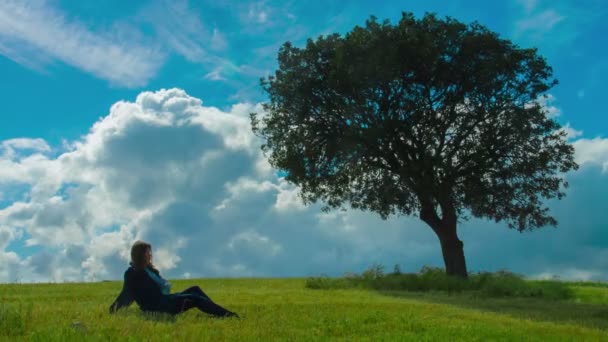 Mladá žena užívat samoty pod stromečkem. Relaxace, sám s přírodou — Stock video