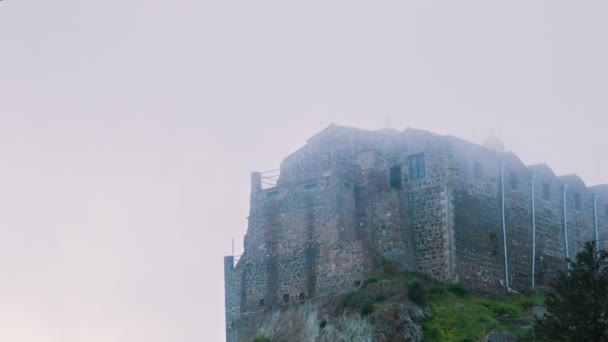Régi kő kolostor állt a magas dombon rejtett a ködben. Ókori építészet — Stock videók