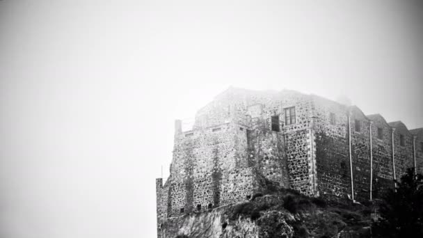 Черно-белый таинственный замок с привидениями, стоящий на туманной вершине горы — стоковое видео
