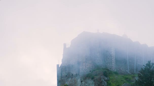 Antiguo monasterio ortodoxo en la cima de la montaña. Edificio de piedra brumoso de pie en la colina — Vídeos de Stock