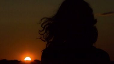 Yalnız genç kadın arıyor, günbatımı, düşünme, Rüzgar saçlarını ile oynamak