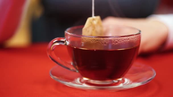 Hospodyňka tvorby černého čaje pomocí levné čajové sáčky. Žena sedí u stolu — Stock video